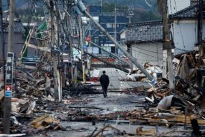 seorang-pria-berjalan-di-sepanjang-jalan-asaichi-dori-yang-terbakar-akibat-gempa-bumi-di-wajima-jepang-4-januari-2024